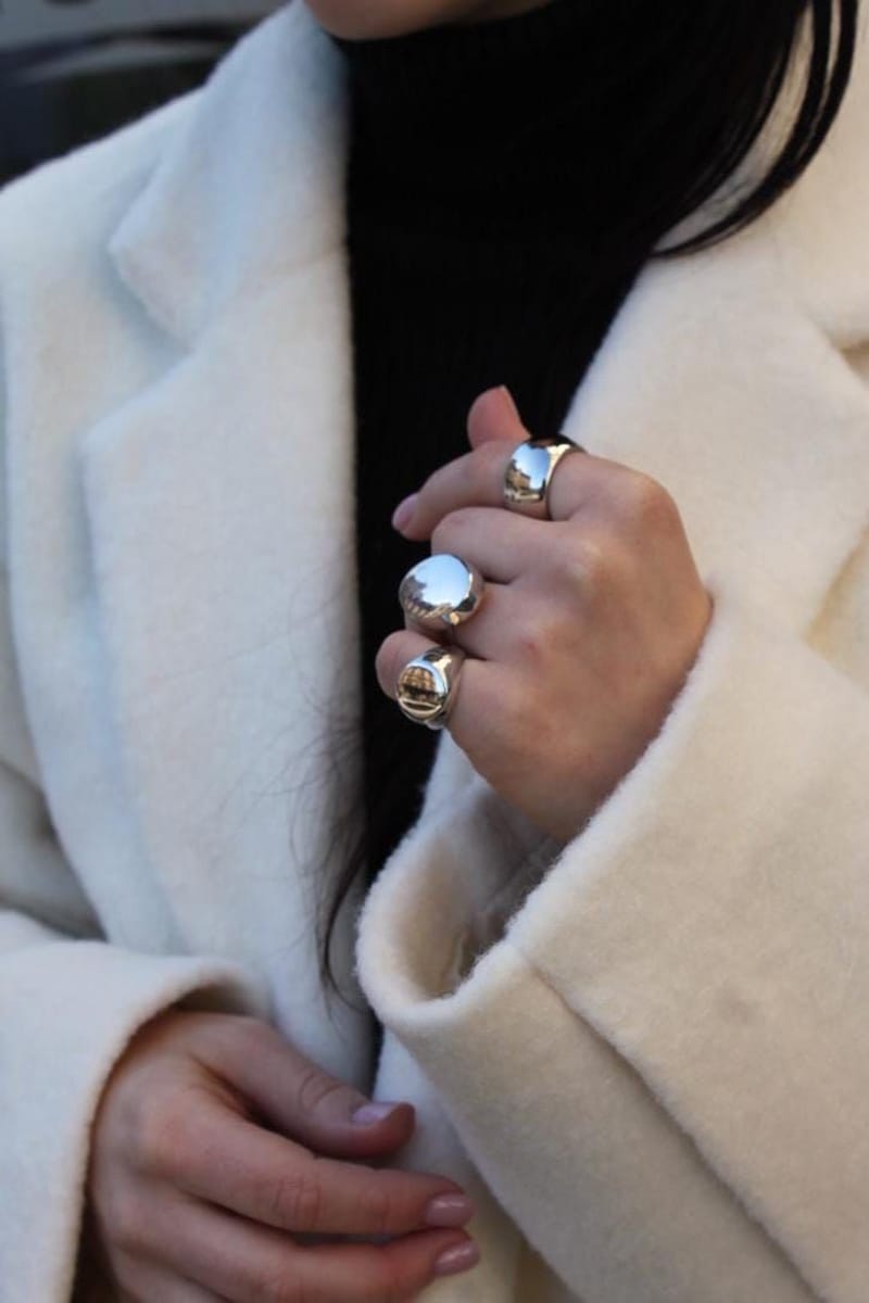 Maxi bagues argent portées avec manteau blanc automne hiver 2025