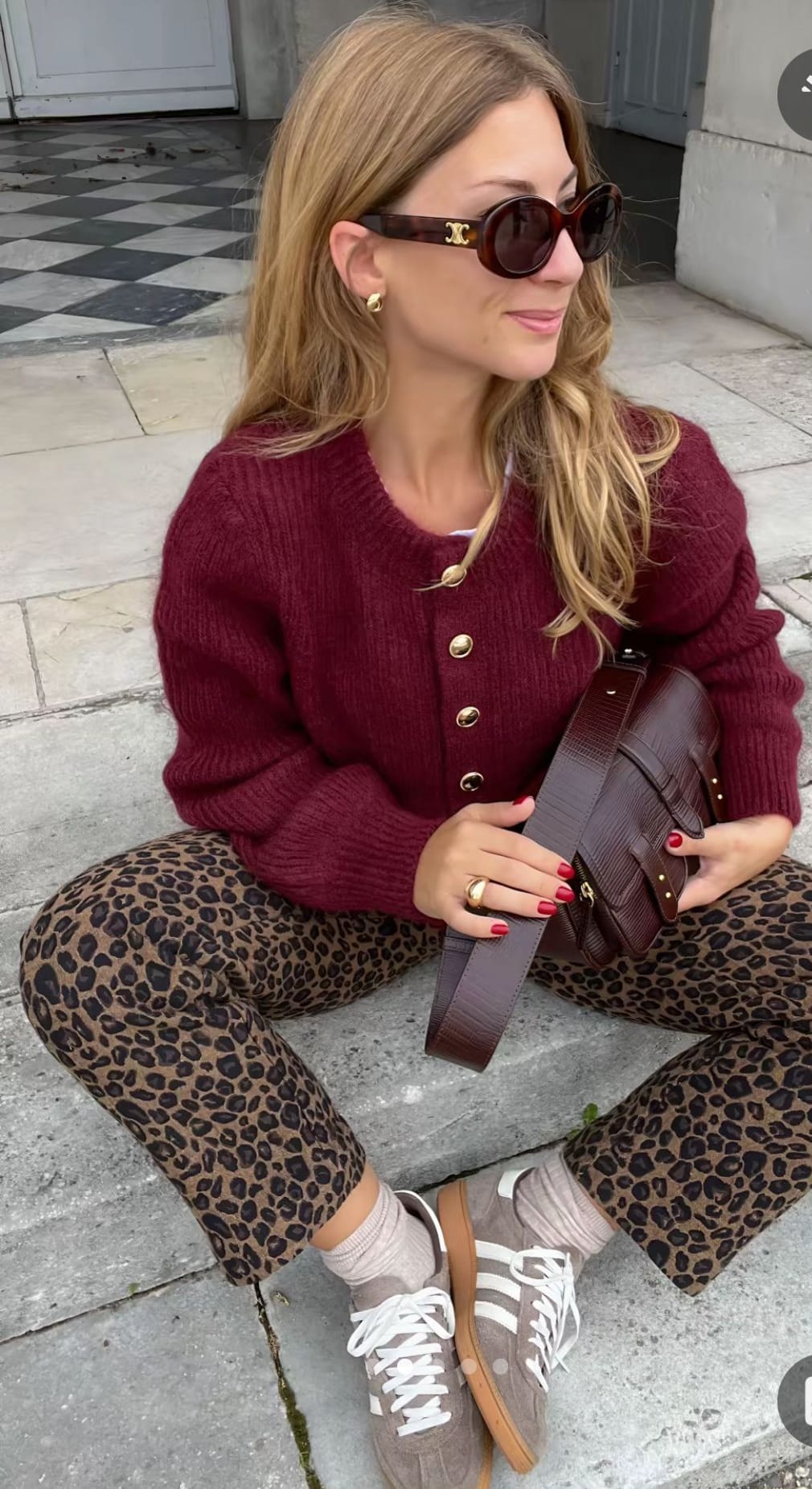 Streetstyle automne chic avec cardigan bordeaux à boutons dorés, pantalon imprimé léopard, sac marron et baskets rétro beiges, style décontracté et tendance.