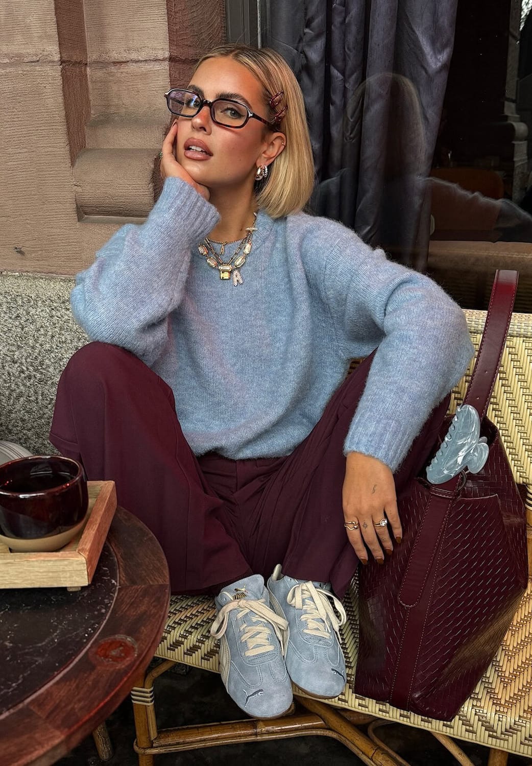 Femme en pull bleu ciel et pantalon bordeaux avec baskets pastel, look hiver 2026 tendance couleurs