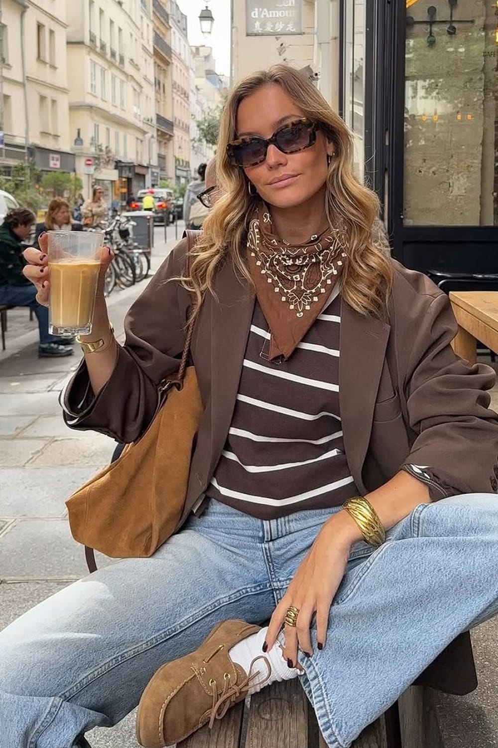 Bandana à motifs cachemire noué autour du cou sur un pull rayé marron et un blazer oversize
