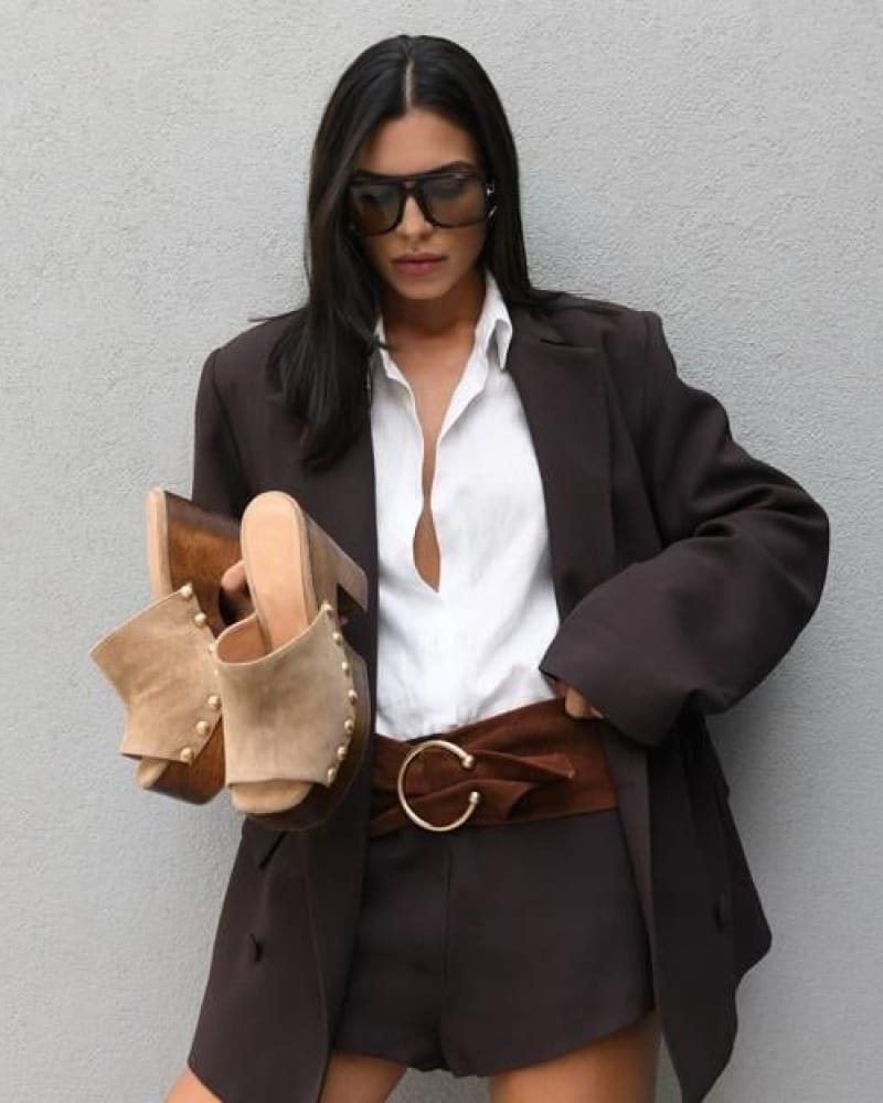Ceinture large en daim brun à boucle dorée XXL portée sur une chemise blanche et un blazer chocolat