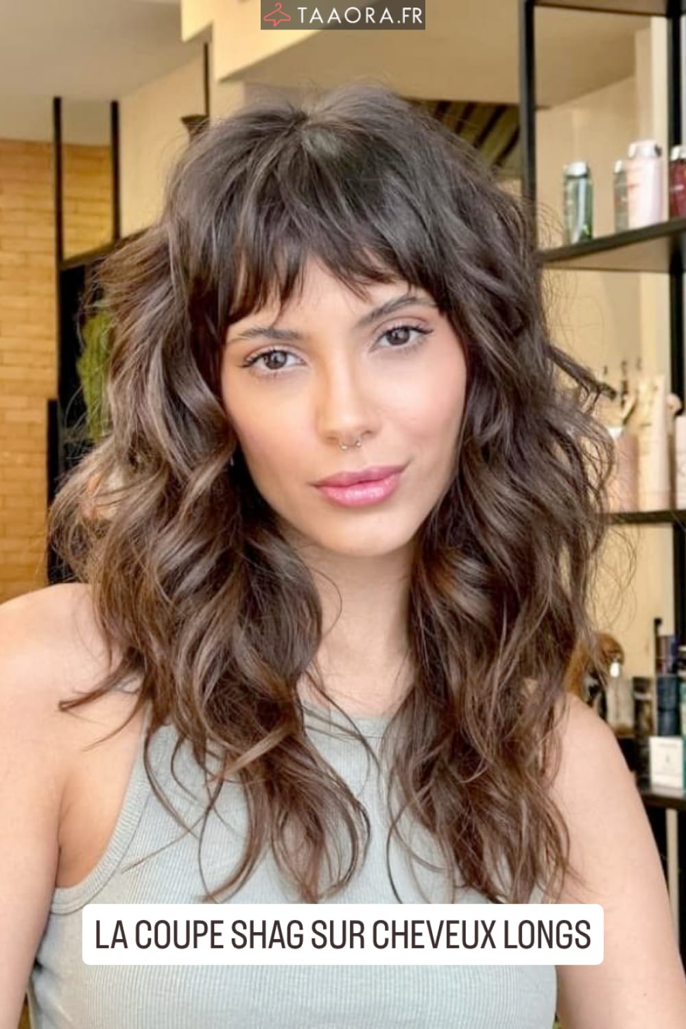 Coupe shag longue avec bangs effilés et boucles naturelles sur cheveux bruns