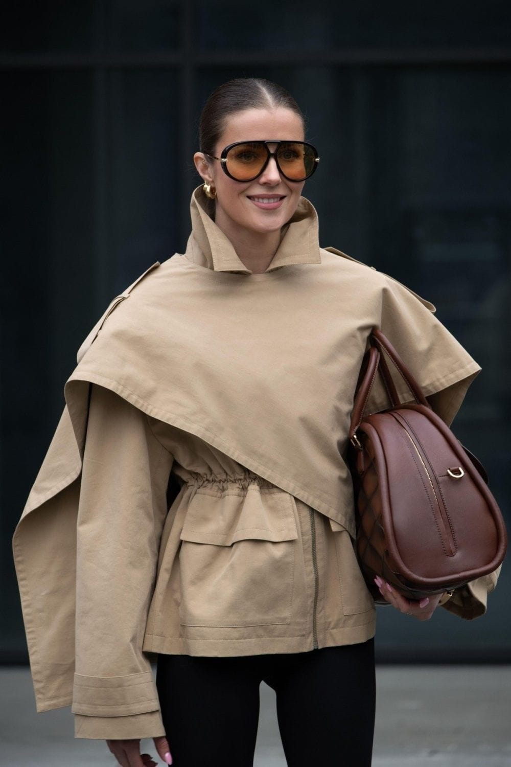 Lunettes aviator oversize à verres ambrés portées avec un trench camel et un sac en cuir brun