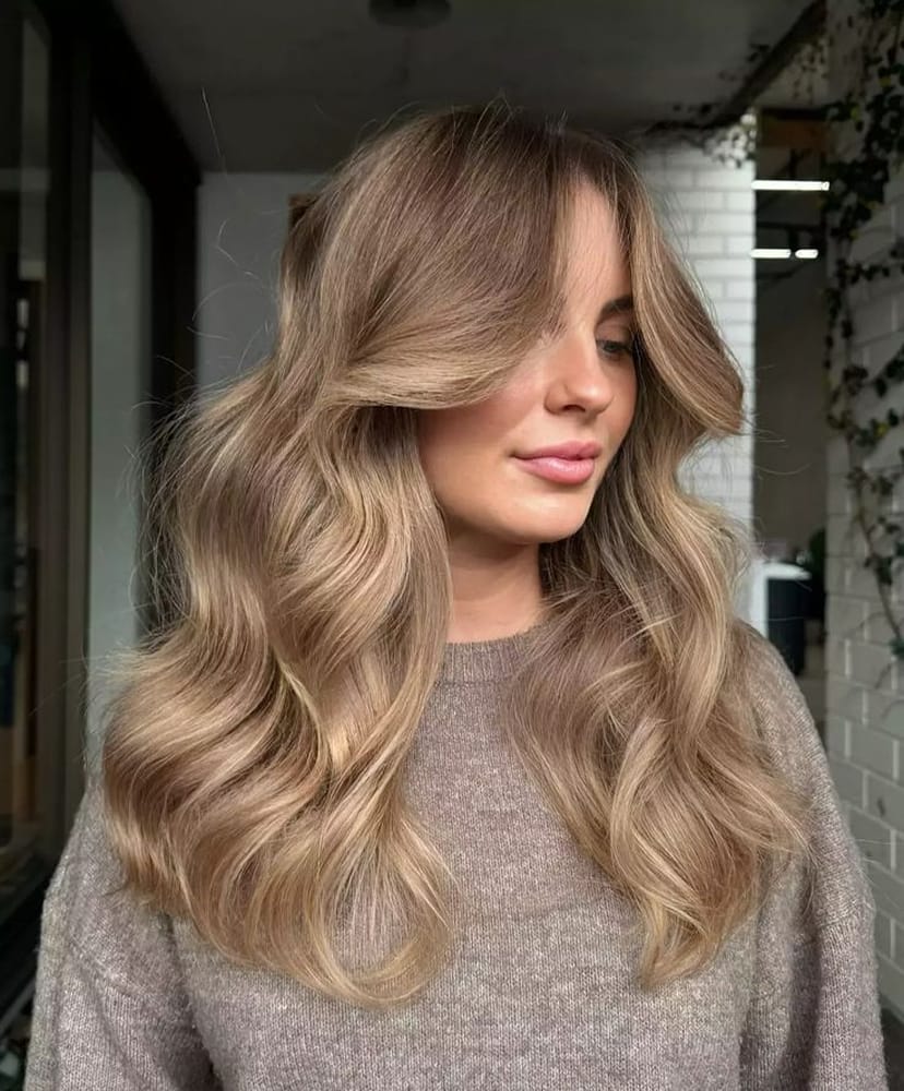 Coiffure cheveux longs blond bronde ondulés mêlant des tons miel, caramel et toffee