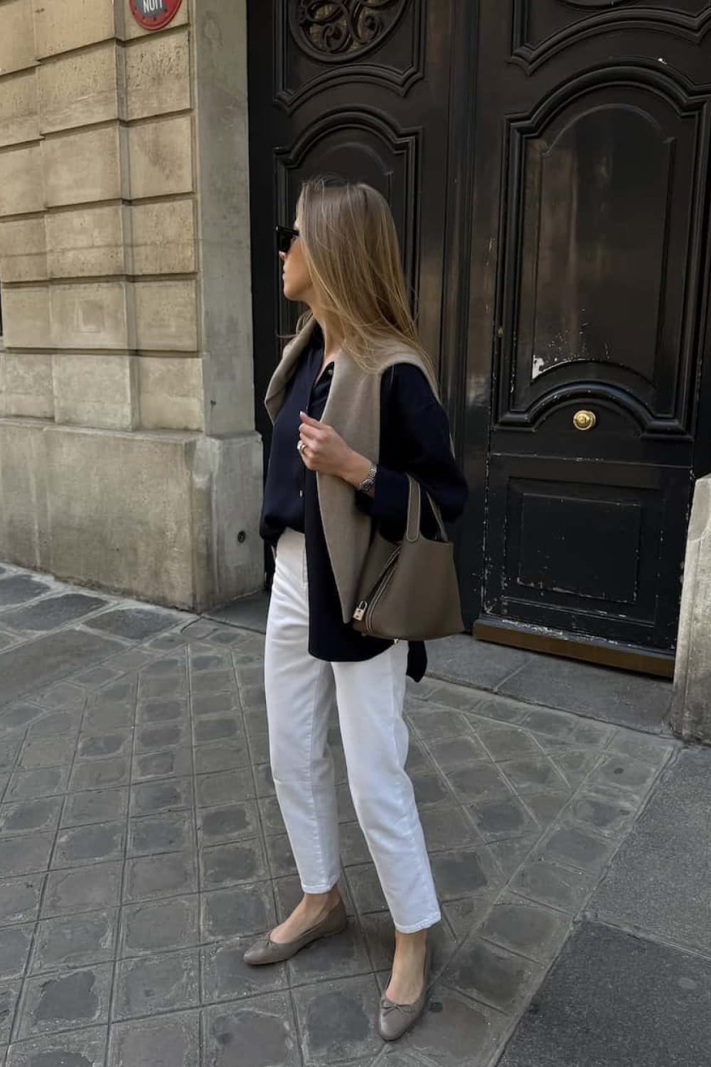 Look femme minimaliste printemps haut bleu marine, jean blanc avec ballerines et sac camel