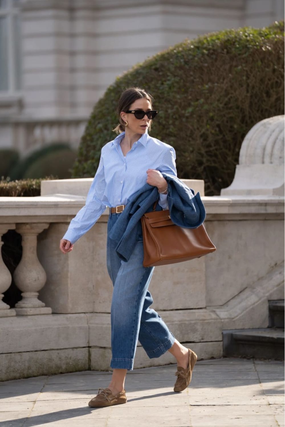 Mocassins bateau en suède camel avec un jean large et une chemise rayée bleue : look printemps tendance