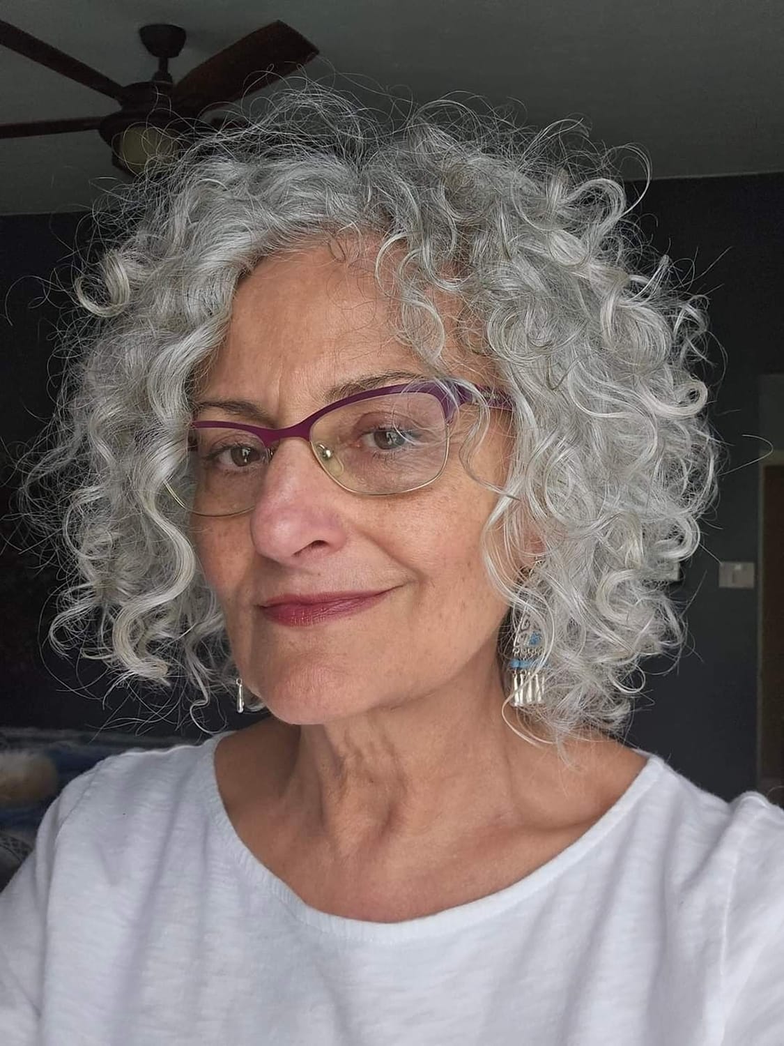 Cheveux gris bouclés mi-longs avec spirales définies, femme mature avec lunettes