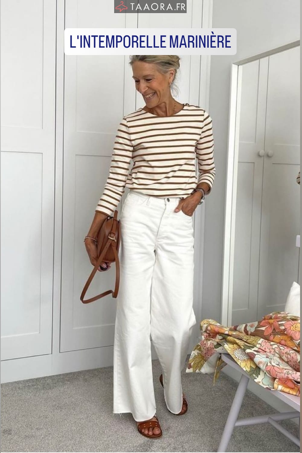 Mode femme printemps 60 ans : jean blanc large à jambe ample associé à une marinière rayée marron et blanc et des sandales plates cuir