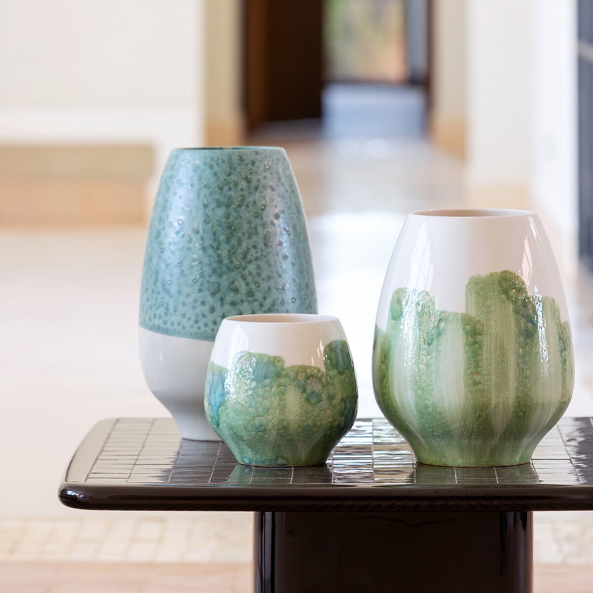  Trois vases bicolores en faïence émaillée aux nuances vertes et céladon posés sur une table