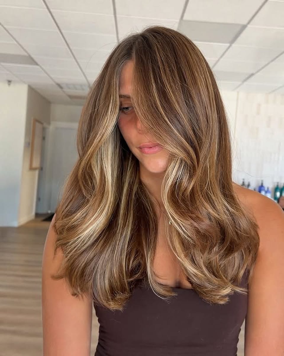 Balayage bronde miel et caramel sur cheveux longs châtains avec mèches lumineuses