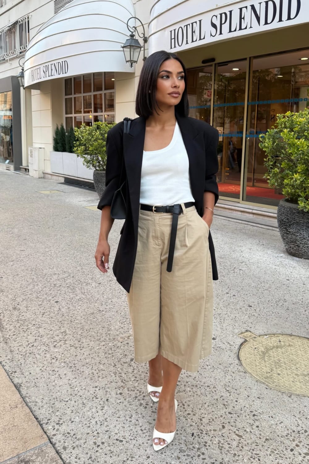 Blazer noir avec pantalon large beige, top blanc et sandales blanches, look chic pour l’été et la rentrée.