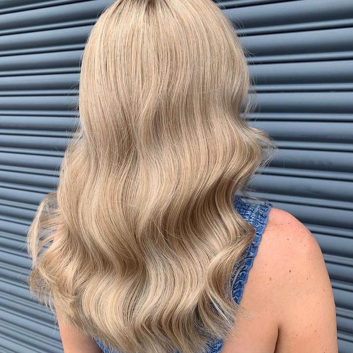 Blond champagne sur cheveux longs ondulés avec reflets beige et dorés
