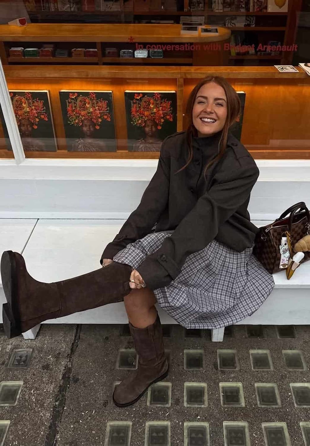 Tenue tendance automne 2026 avec jupe à carreaux, veste noire et bottes hautes marron