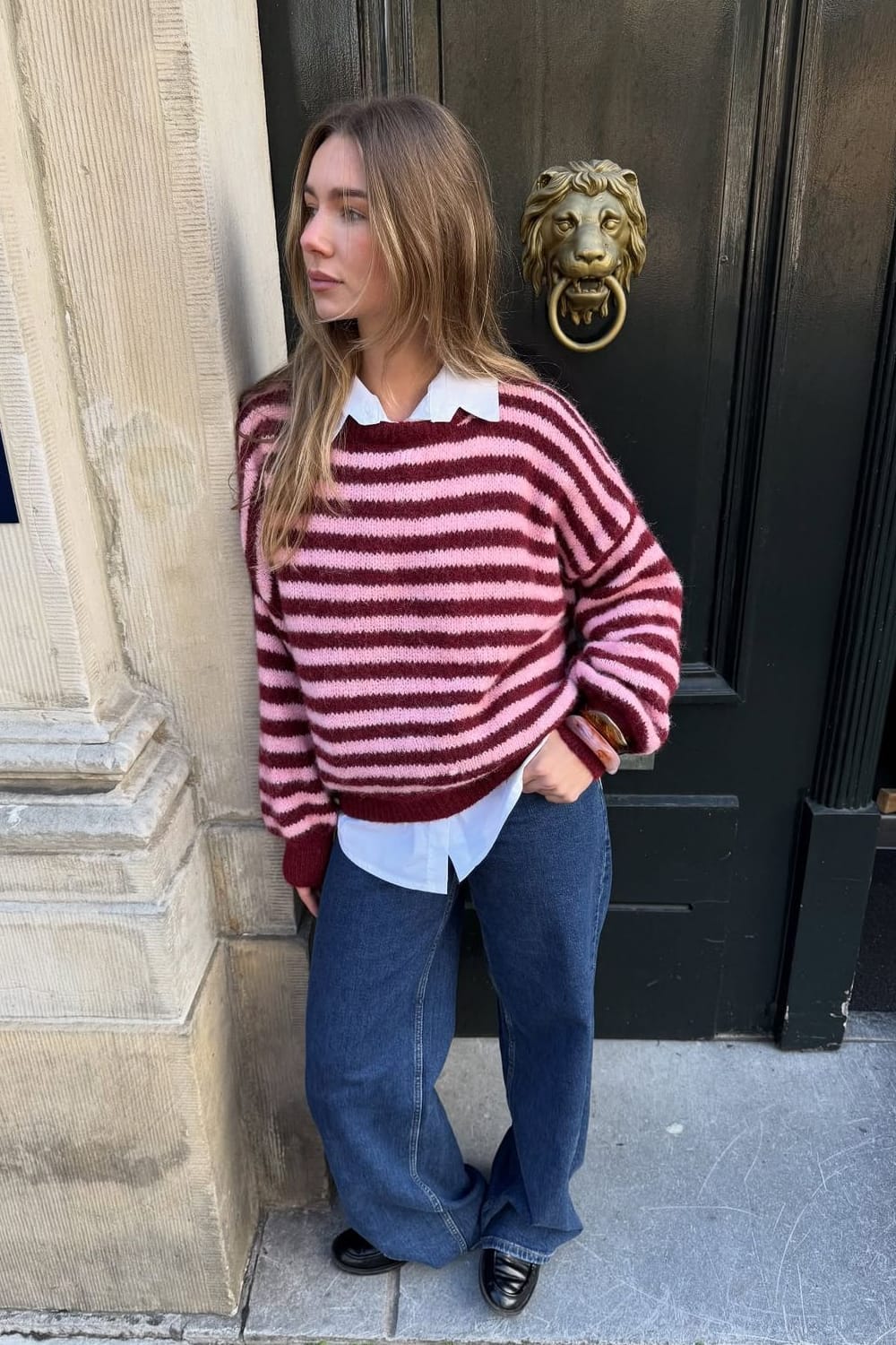 Tenue tendance automne 2026 avec pull rayé rose et bordeaux, chemise blanche et jean wide leg