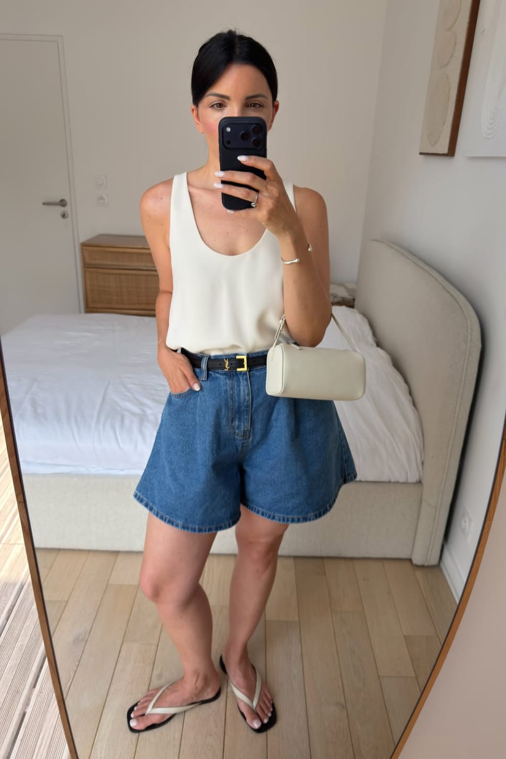 Short en jean bleu avec débardeur crème et sandales plates, tenue d’été facile à porter.