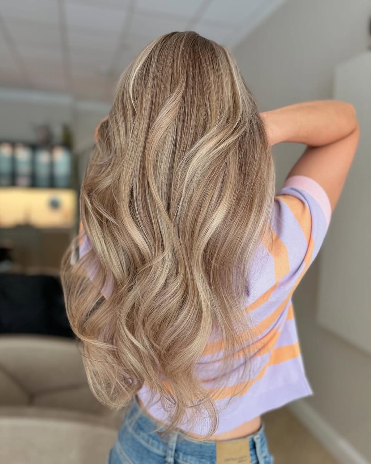 Coloration teddy bear blonde sur cheveux longs ondulés avec reflets miel et beige doré