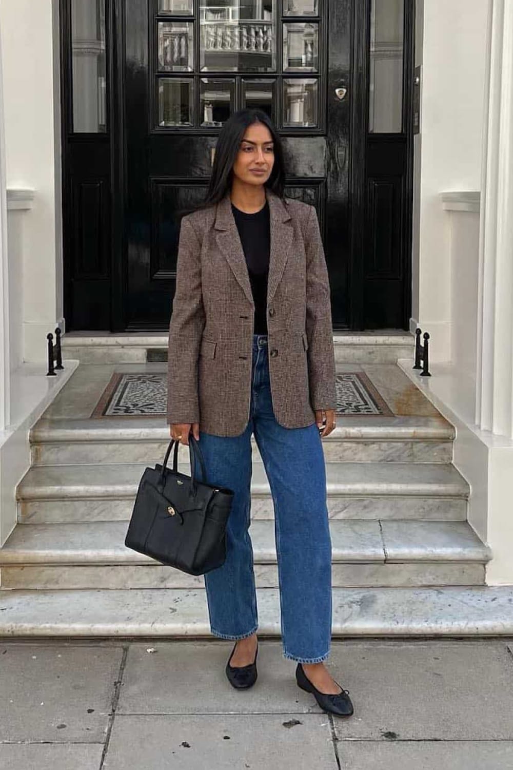 Blazer à carreaux marron porté avec un t-shirt noir, un jean droit bleu et des ballerines noires en automne