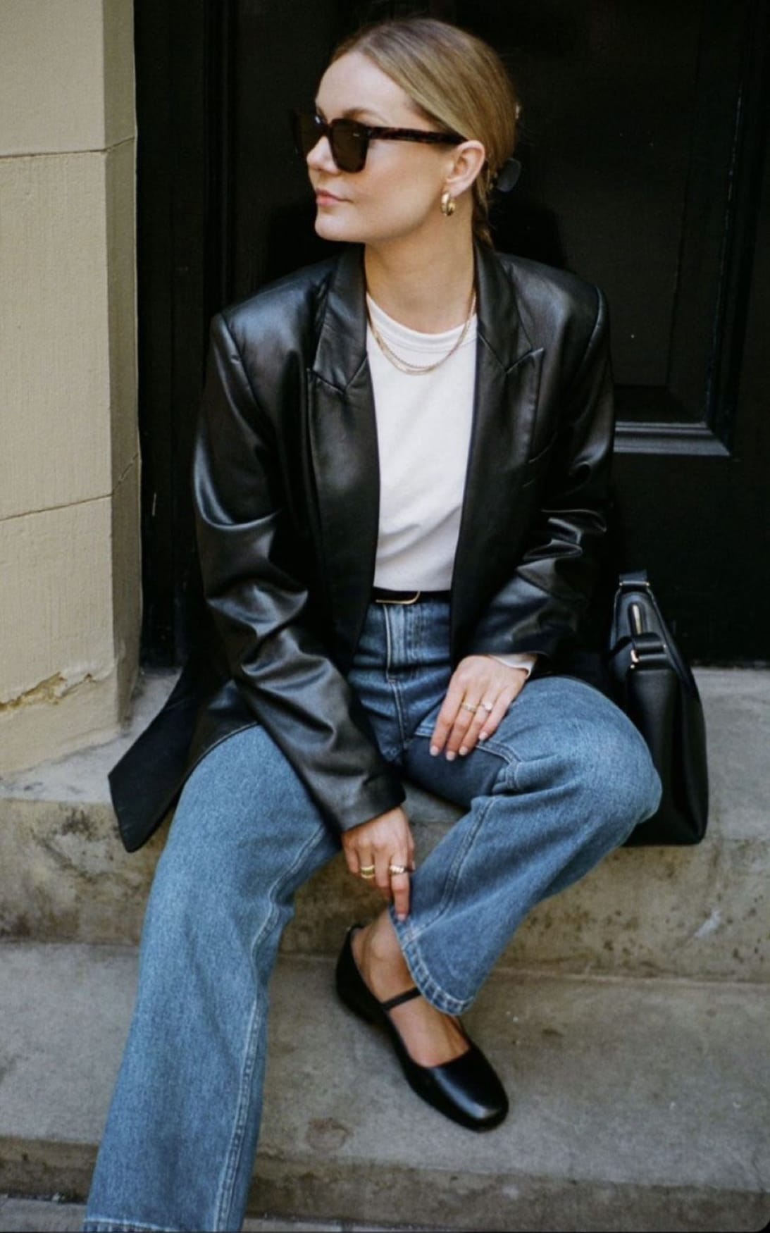 Blazer en cuir noir oversize porté avec un t-shirt blanc, un jean droit clair et des babies noires en automne