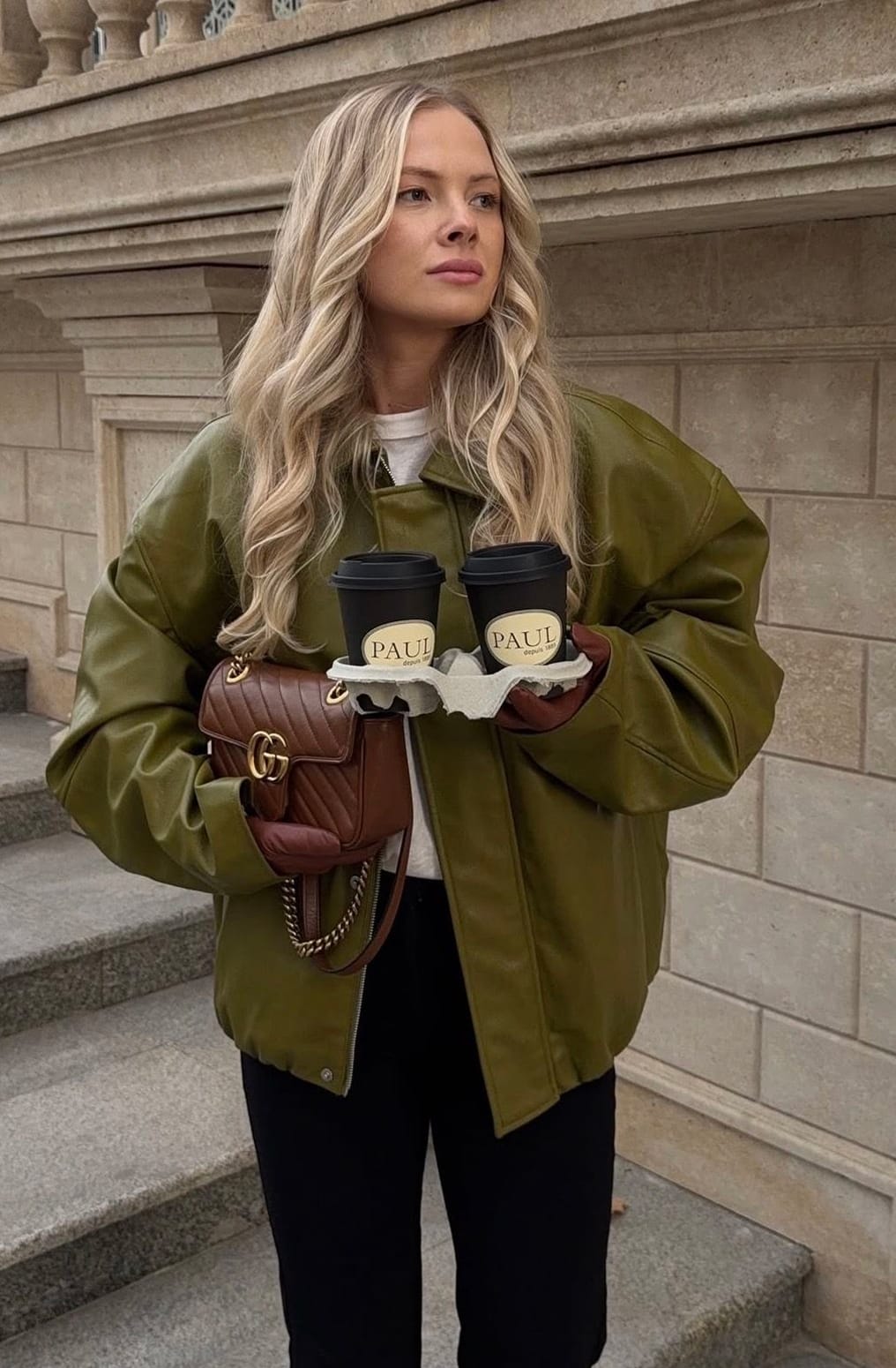 Blouson en cuir vert olive oversize avec un haut blanc, un pantalon noir, des gants et un sac en cuir marron cognac