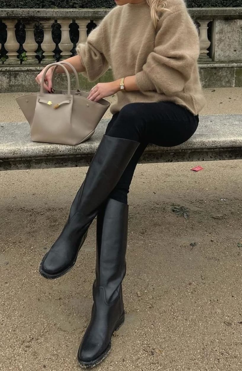 Bottes cavalières noires en cuir portées avec un jean slim, un pull camel et un sac cabas taupe en automne