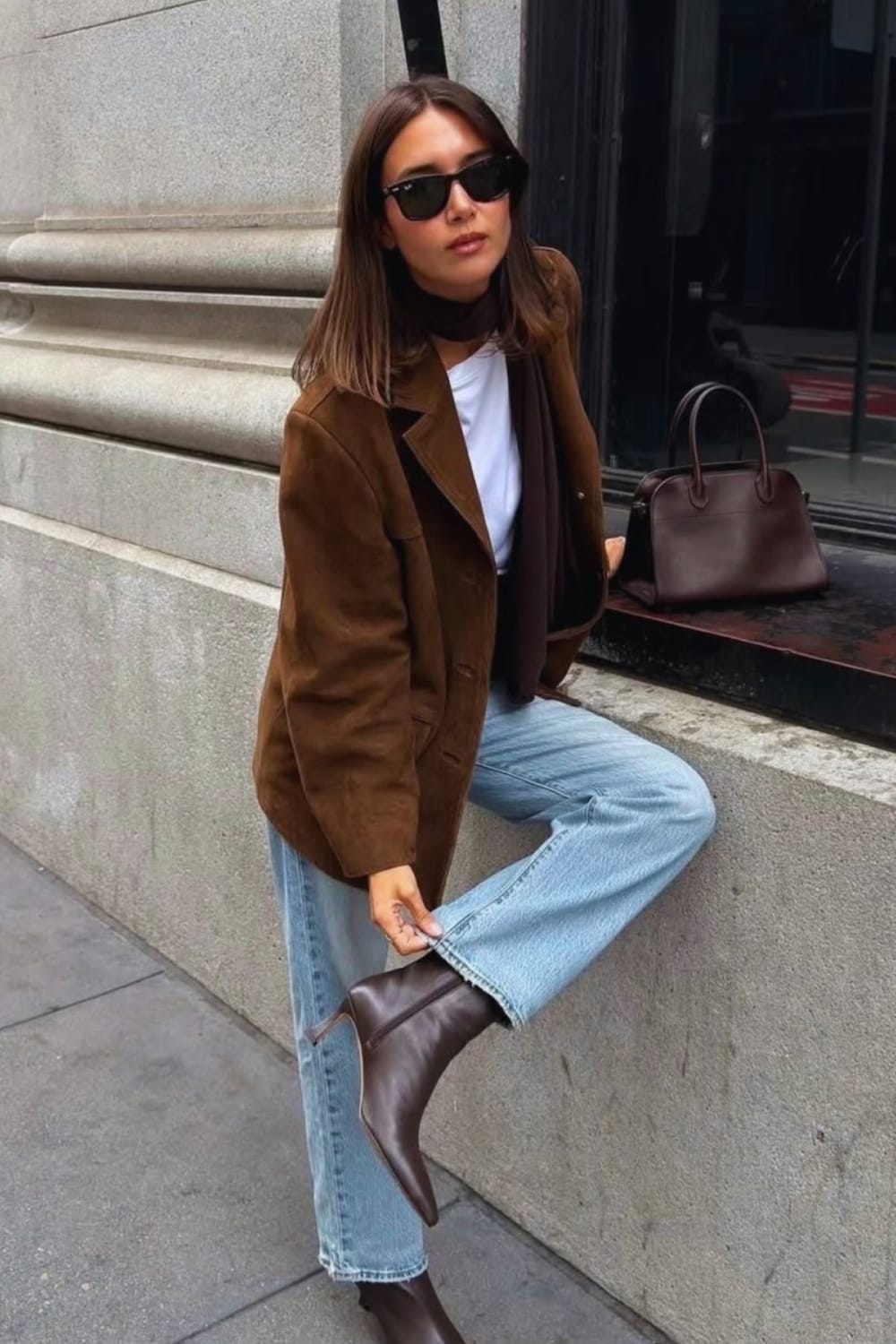 Femme portant un blazer en daim marron oversize avec un tee shirt blanc, une écharpe fine chocolat, un jean droit bleu clair et des bottines pointues en cuir marron