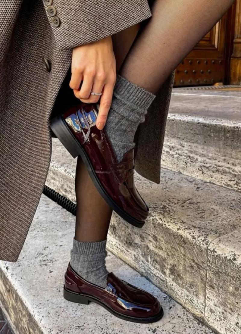 Mocassins vernis bordeaux à semelle épaisse portés avec des chaussettes en laine grise et un manteau en tweed