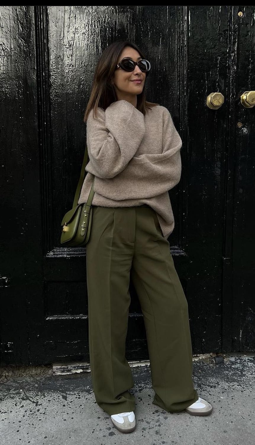 Pantalon large à pinces vert olive porté avec un pull beige oversize, un sac bandoulière en cuir olive et des baskets blanches