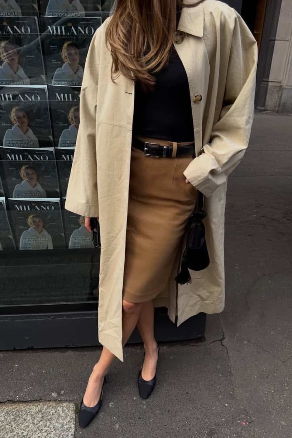 Jupe droite camel sous le genou avec un haut noir, un trench clair et des escarpins noirs.